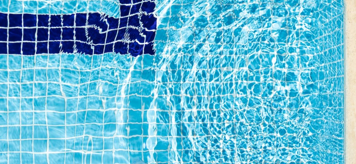 Top view of blue transparent clear calm water surface. Texture with splashes and bubbles. Trendy abstract summer nature background with swimming pool. Flat lay