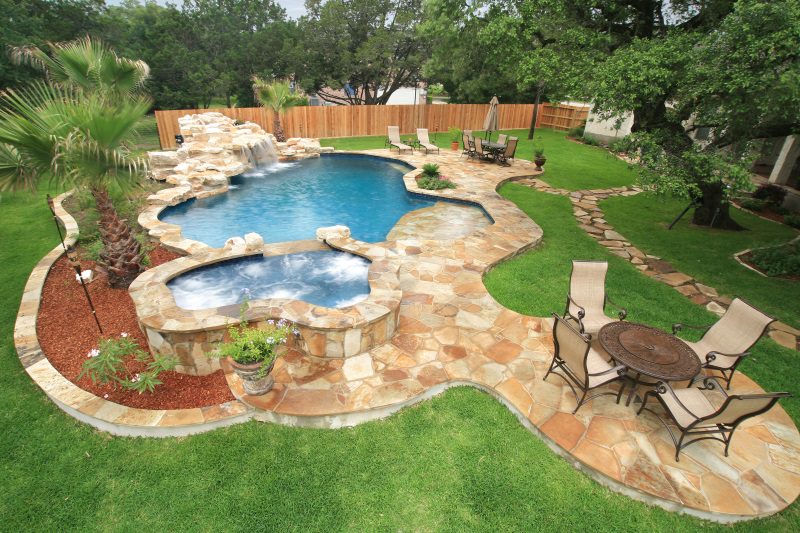 Freeform-with-raised-flagstone-faced-spa-and-large-grotto-hill-country-rock-waterfall
