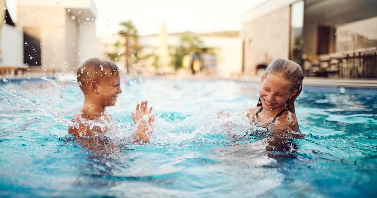 Two children laughing and splashing in a clean, clear outdoor AOP pool enjoying swimming without chlorine irritation or skin sensitivity
