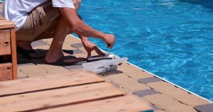Pool water testing kit being used at the edge of a clear swimming pool to check chemical levels