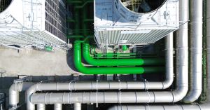 Aerial view of industrial cooling towers and piping where biofilm and microbial growth can develop