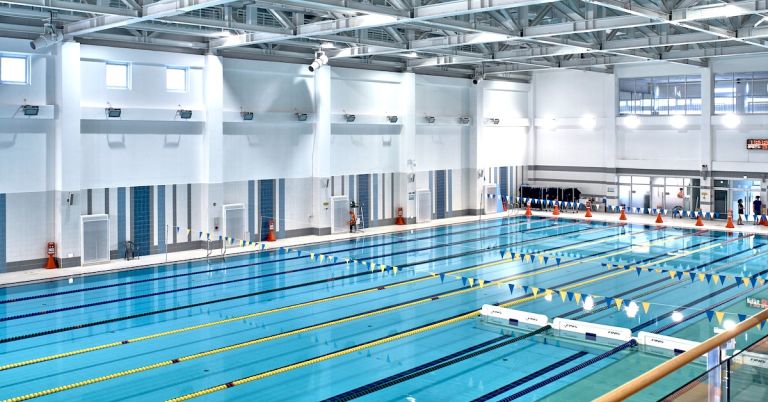 Large indoor Olympic-sized swimming pool for competition with multiple lap lanes and starting blocks