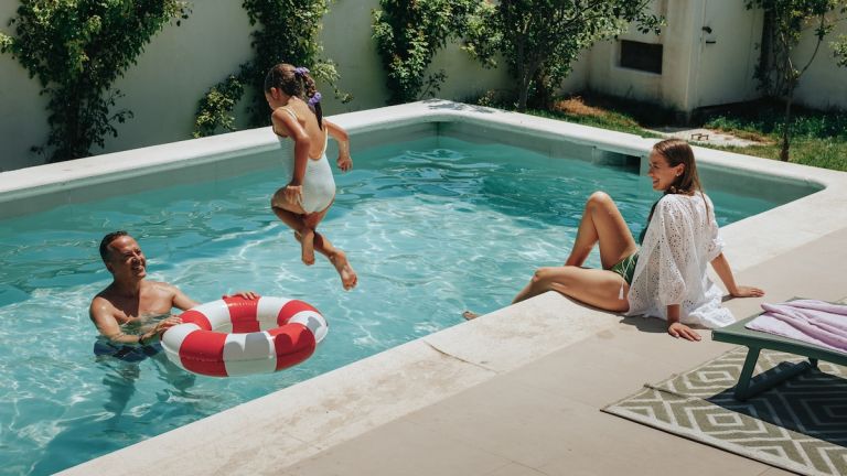 Family enjoying the best pool temperature for swimming on a sunny day in their backyard pool.